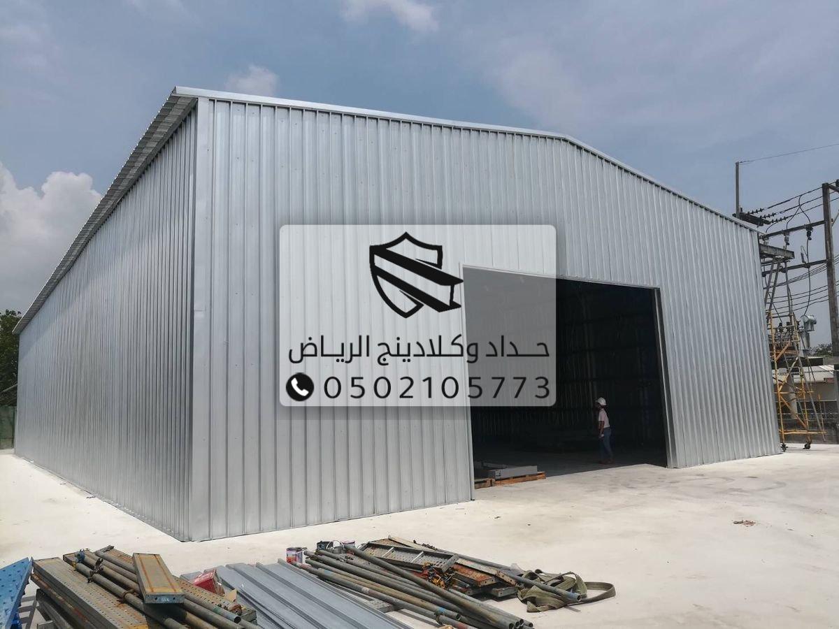 عمال يقومون بتركيب هيكل هنجر معدني في موقع المشروع